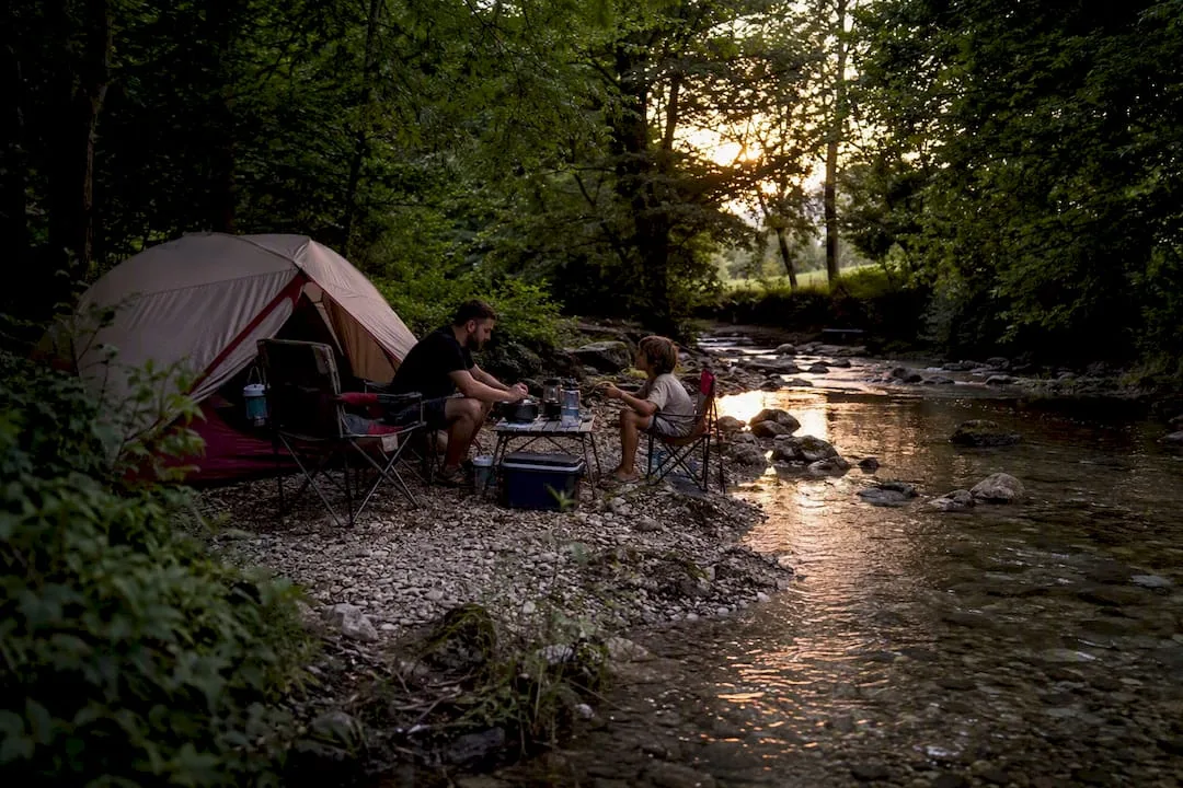 Campsite by a river in a forested Slovenian landscape
